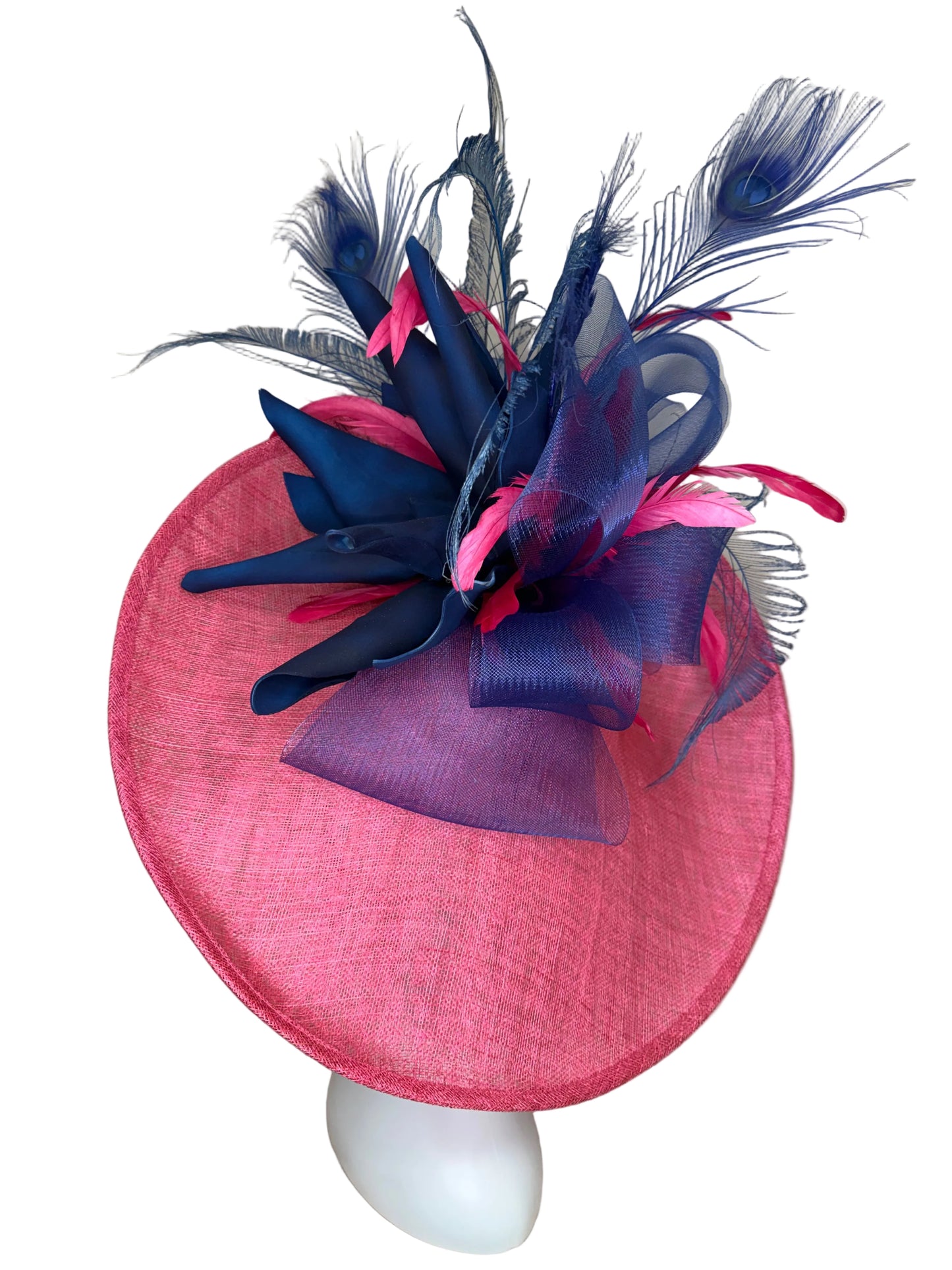 Pink hat with blue and pink feather decorations on a beige surface