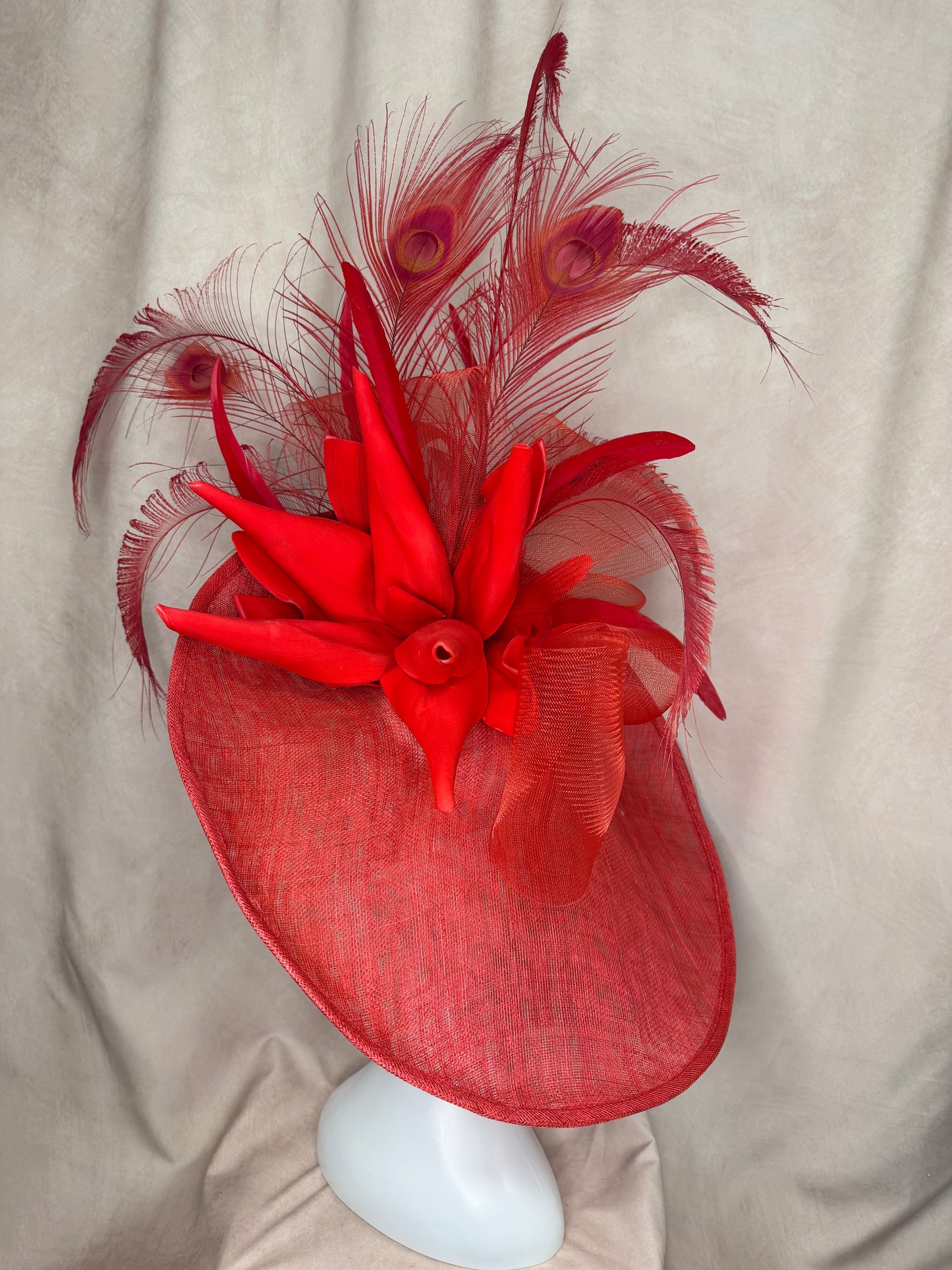 Red decorative headpiece with feathers on a beige surface