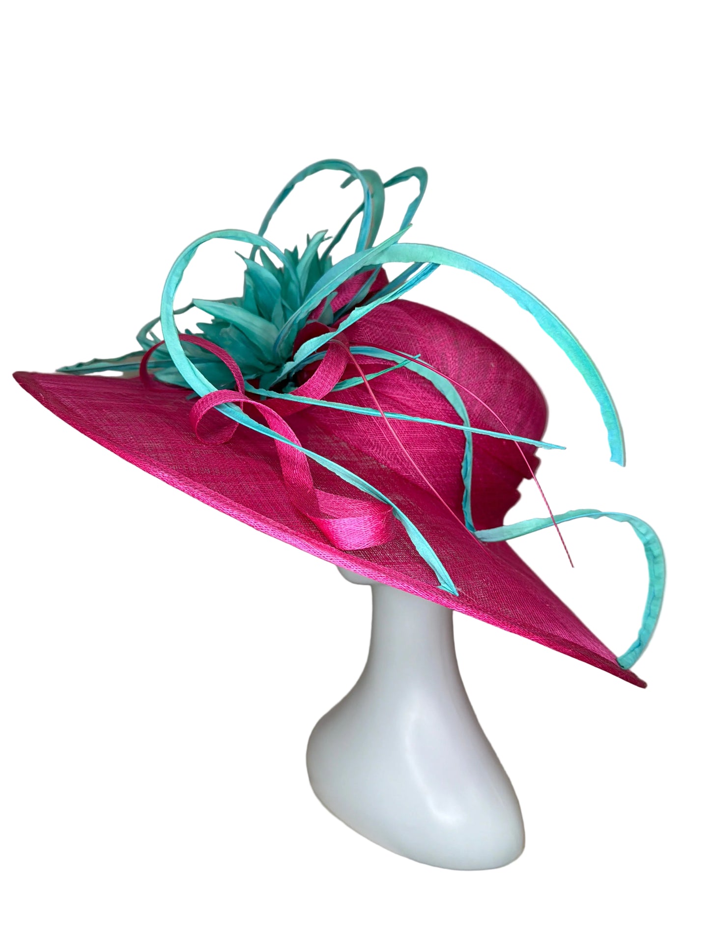 Pink decorative hat with green ribbons on a white mannequin head against a beige background