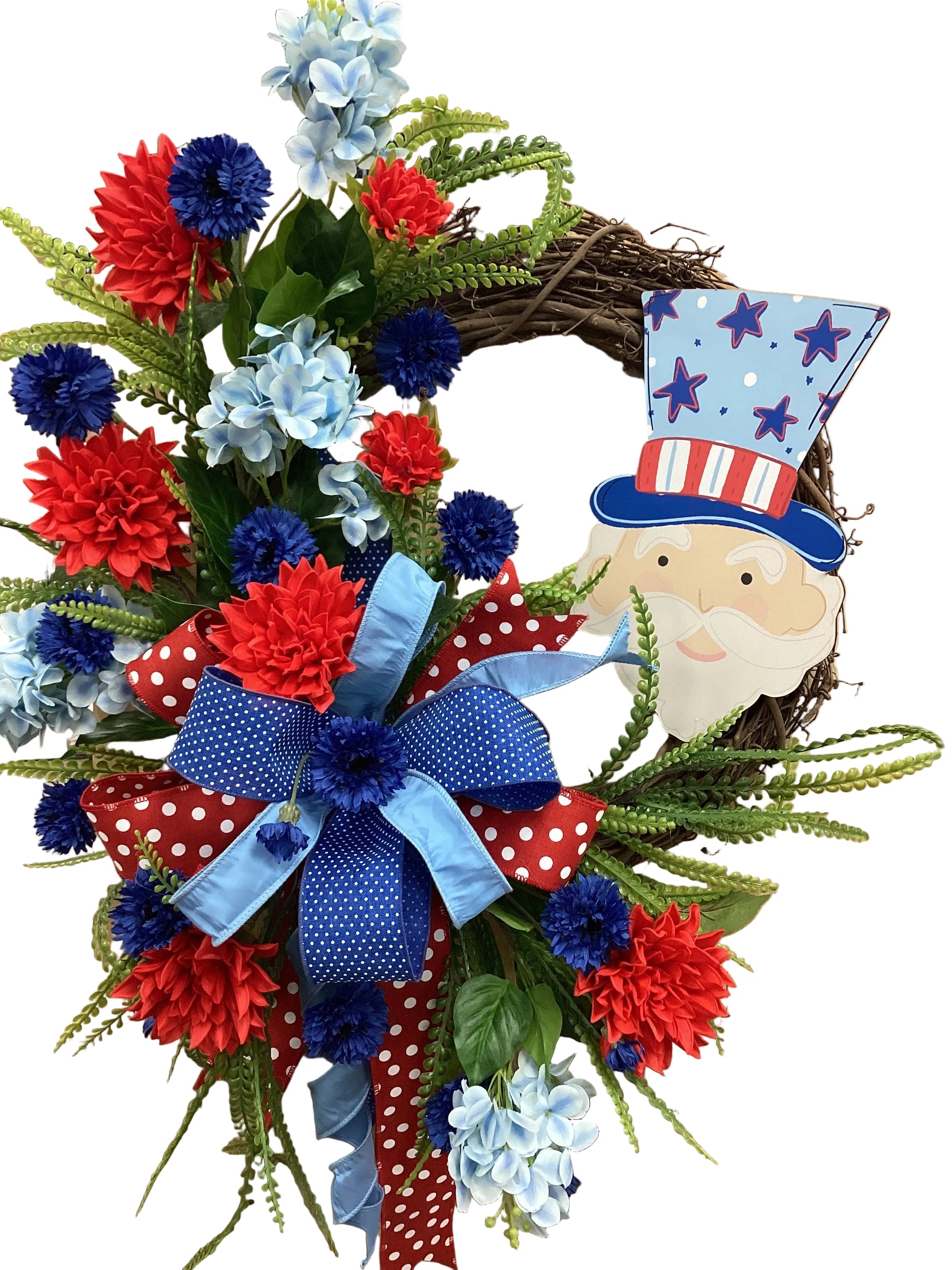 Decorative wreath with red, white, and blue flowers and a Santa Claus figure on a wooden surface.