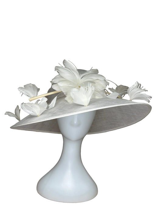 White decorative hat with feathers on a mannequin head against a brown background
