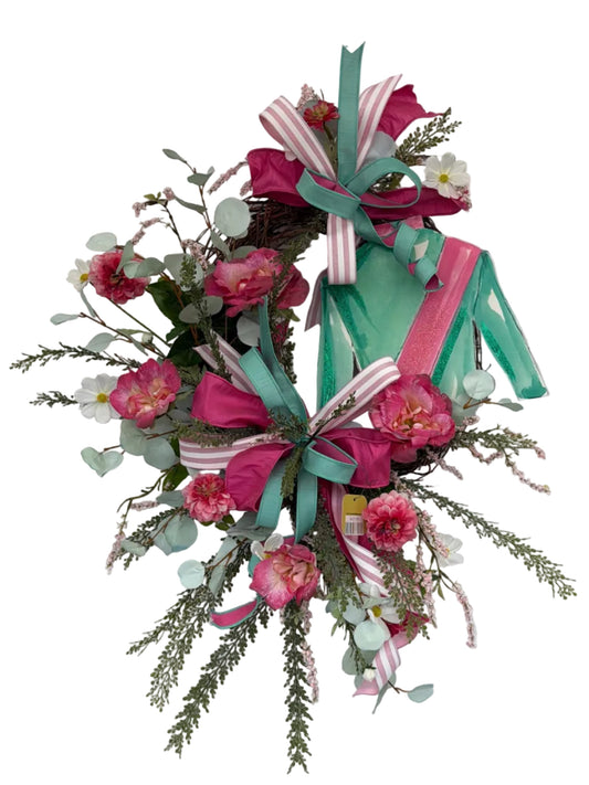 Decorative wreath with flowers and ribbons on a white wooden door.