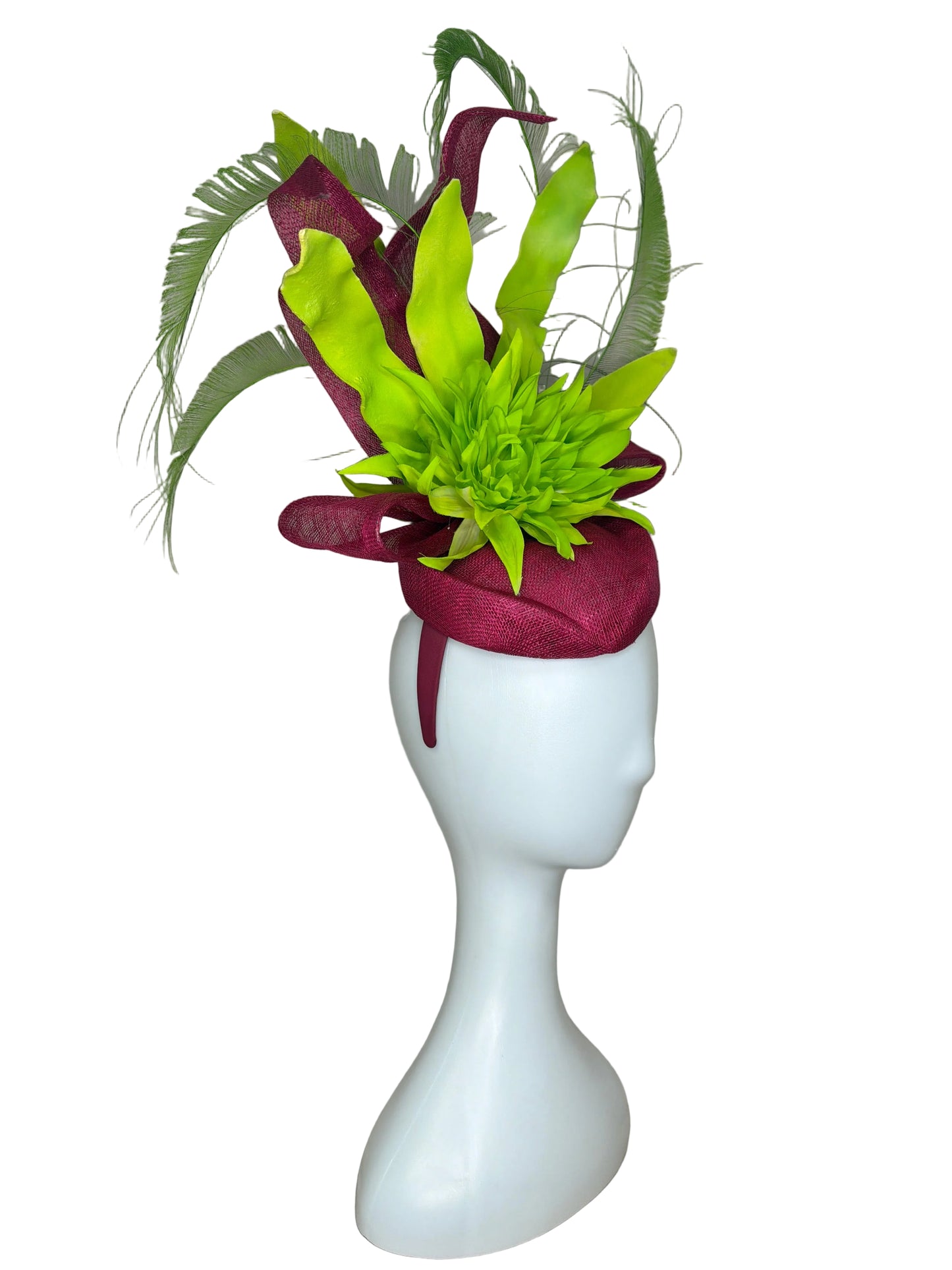 Mannequin head with a decorative headband featuring green flowers and maroon fabric on a beige background.