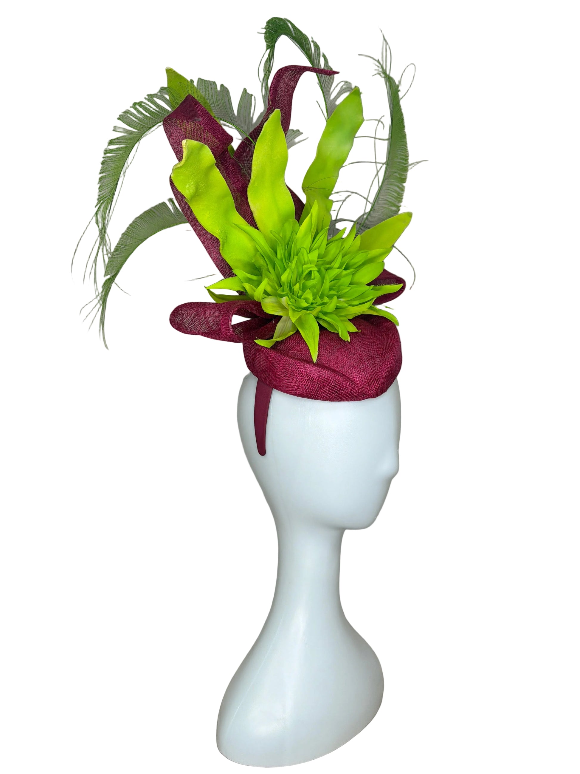 Mannequin head with a decorative headband featuring green flowers and maroon fabric on a beige background.