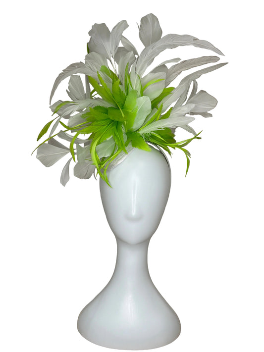 White and green feathered hair accessory on a mannequin head against a brown fabric background