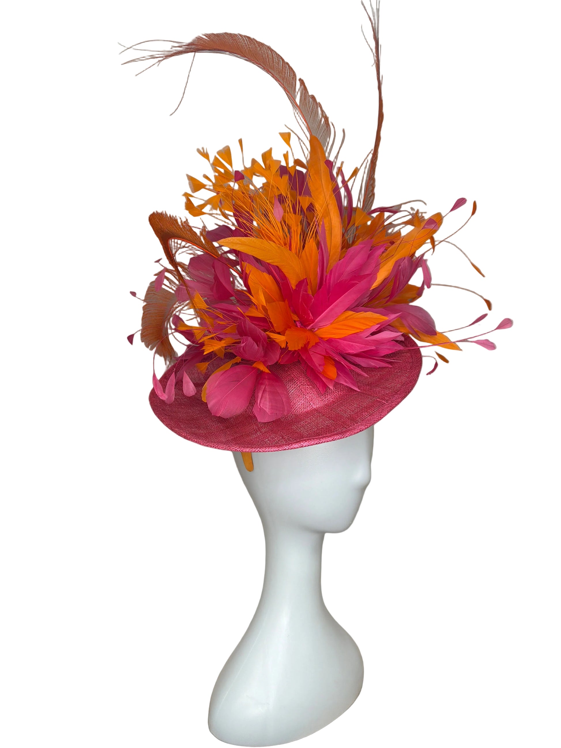 Pink and orange feathered headpiece on a mannequin head against a beige background