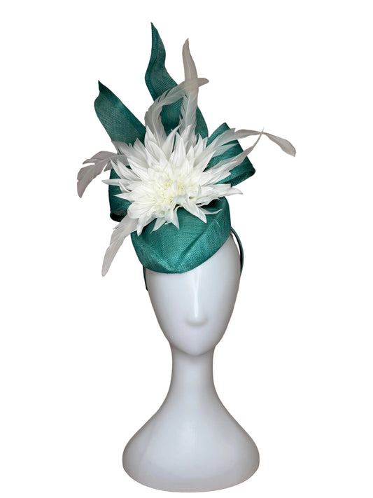 White feathered flower corsage on a mannequin arm with a green ribbon against a beige background