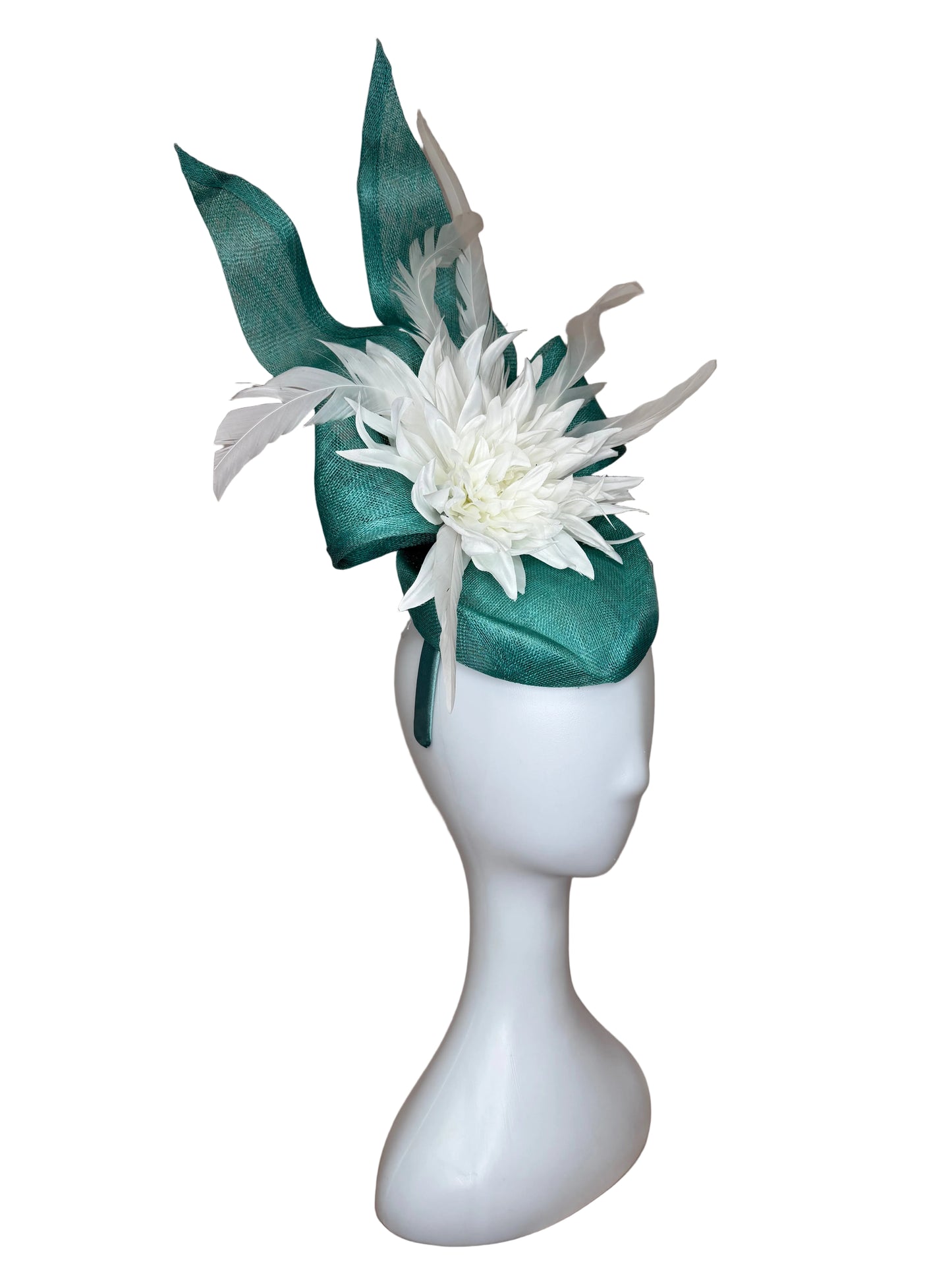 White flower corsage with green ribbon on a mannequin arm against a brown background
