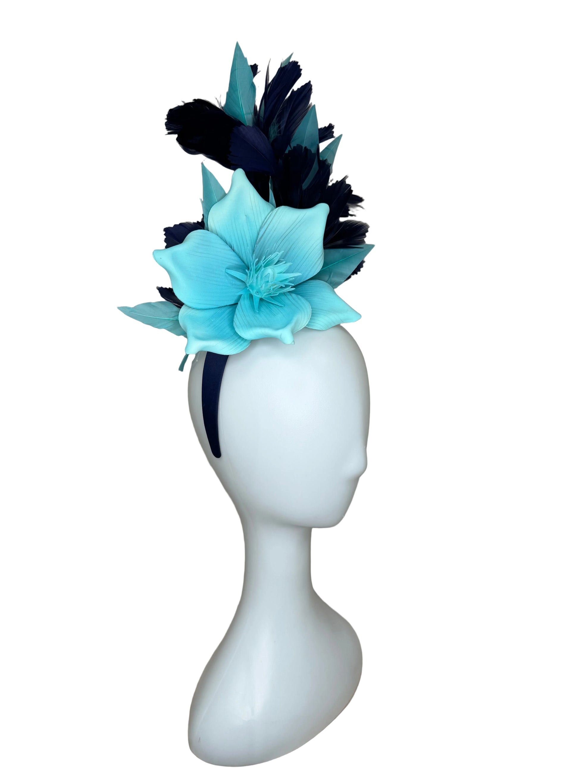 Mannequin head with a blue flower and black feathers on a beige background