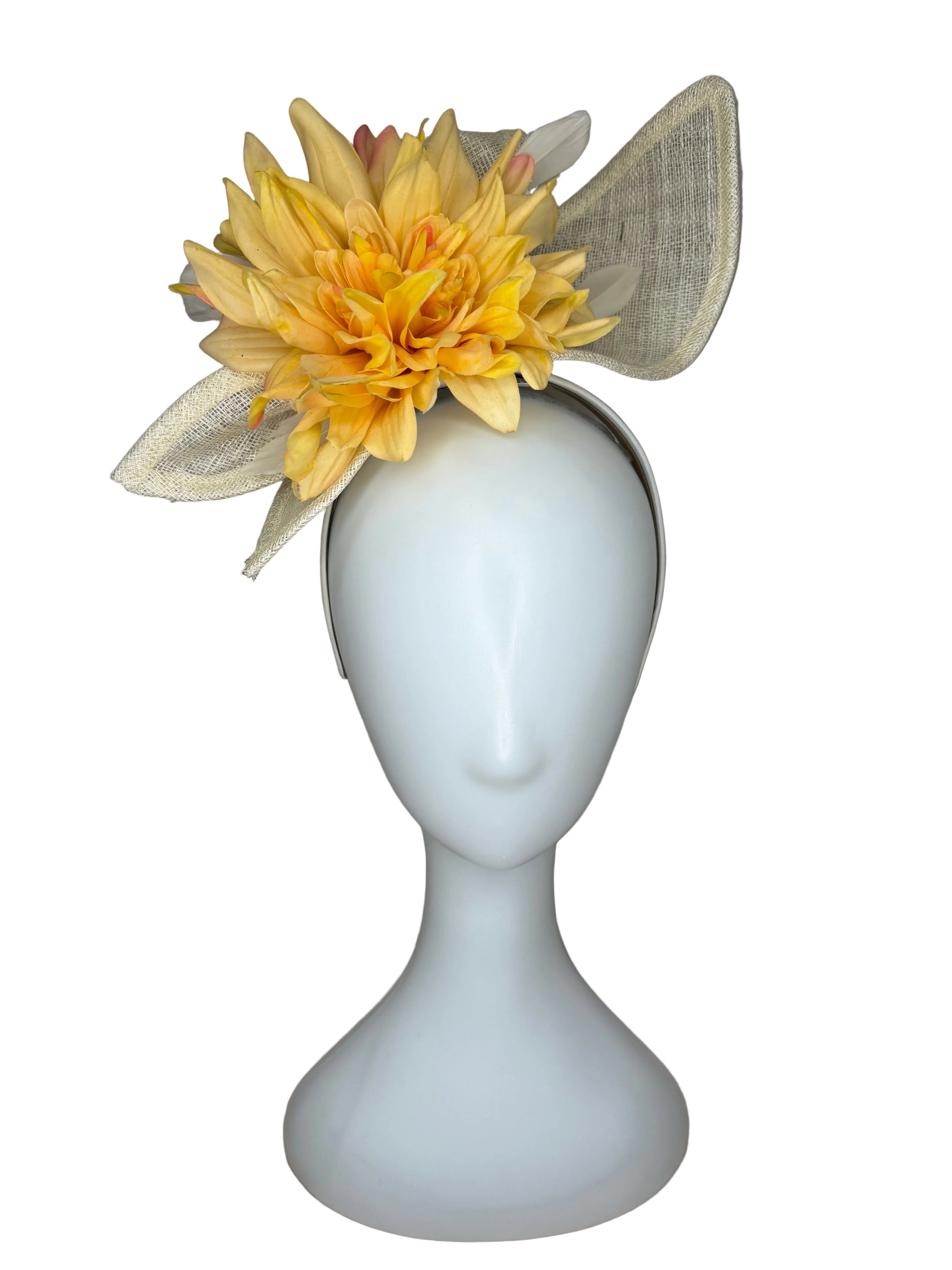 White decorative object with a yellow flower and beige leaves on a gray background