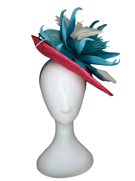 Decorative headband with blue and red feathers on a mannequin head against a beige background