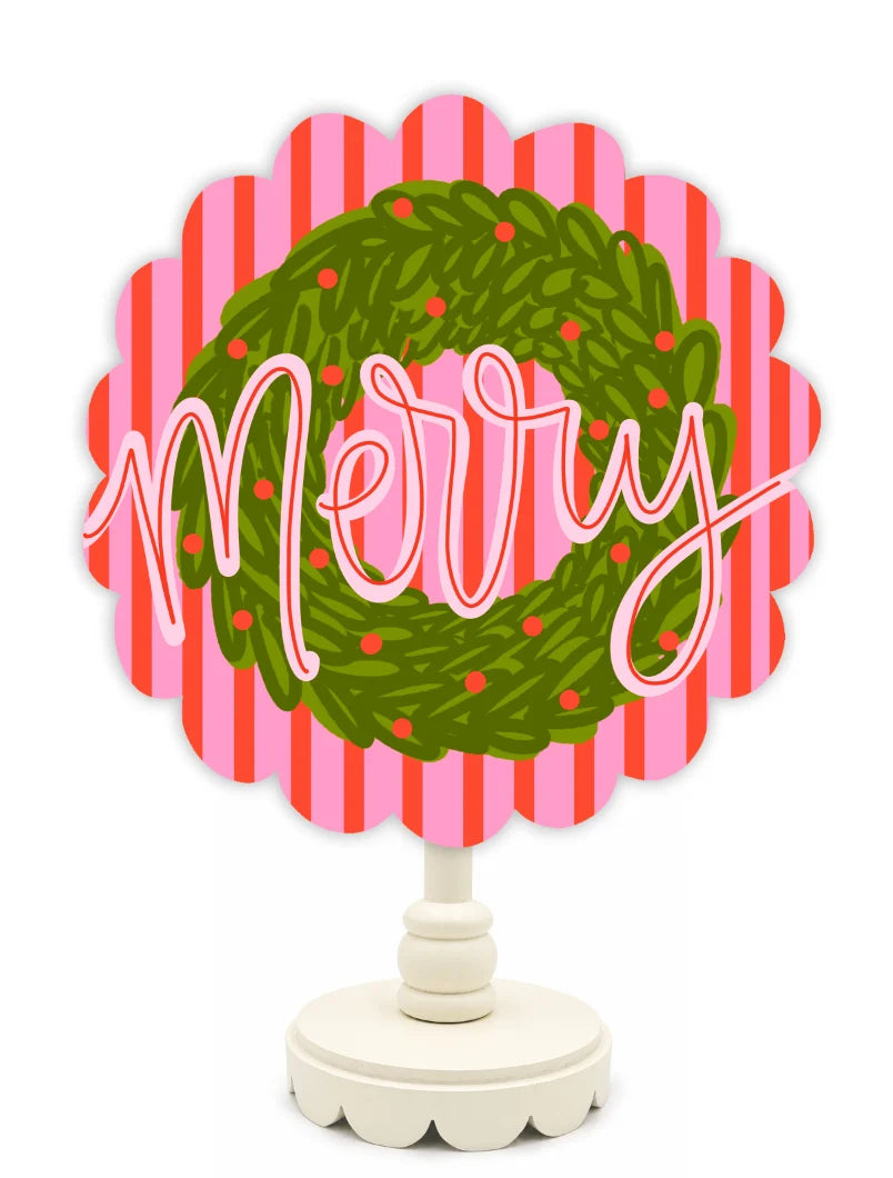 Decorative sign with 'Merry' and a green wreath design on a pink and red striped background.